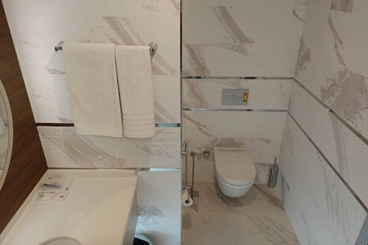 Ein Badezimmer mit Toilette, Handtuchhalter und Duschbereich.