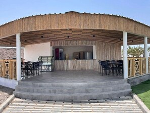 A covered outdoor area with a tiled floor, a counter with a refrigerator, and several chairs. - GADILEH RESORT HOTEL (Tadjoura)