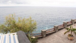 A coastal view with a wooden deck, a railing, and a palm tree. - Blue Views (Charco Azul)