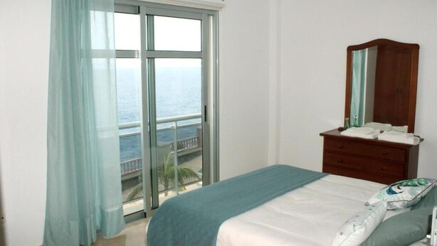 A bedroom with a large window, a bed, a dresser, and a mirror. - Blue Views (Charco Azul)