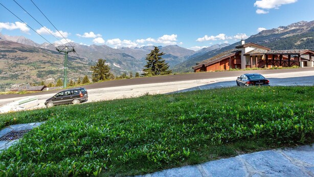 A mountain view with a building and a car on the road.