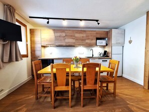 Cozinha compacta com armários de madeira, micro-ondas e cafeteira no balcão.