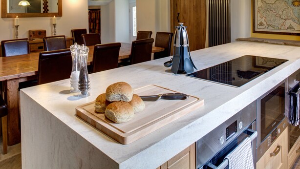 A modern kitchen with a large island, wooden chairs, and a dining area with a wooden table and chairs. - Neddy House (Richmond)