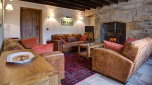A cozy living room with a stone fireplace, leather sofas, and a wooden coffee table. - Neddy House (Richmond)