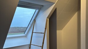 Ein Zimmer mit Oberlicht, einer Holzleiter und einer Steinwand.