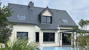 Ein modernes Haus mit Swimmingpool, großen Fenstern und einem gepflegten Rasen.