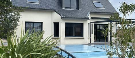 A modern house with a swimming pool, large windows, and a well-maintained lawn.