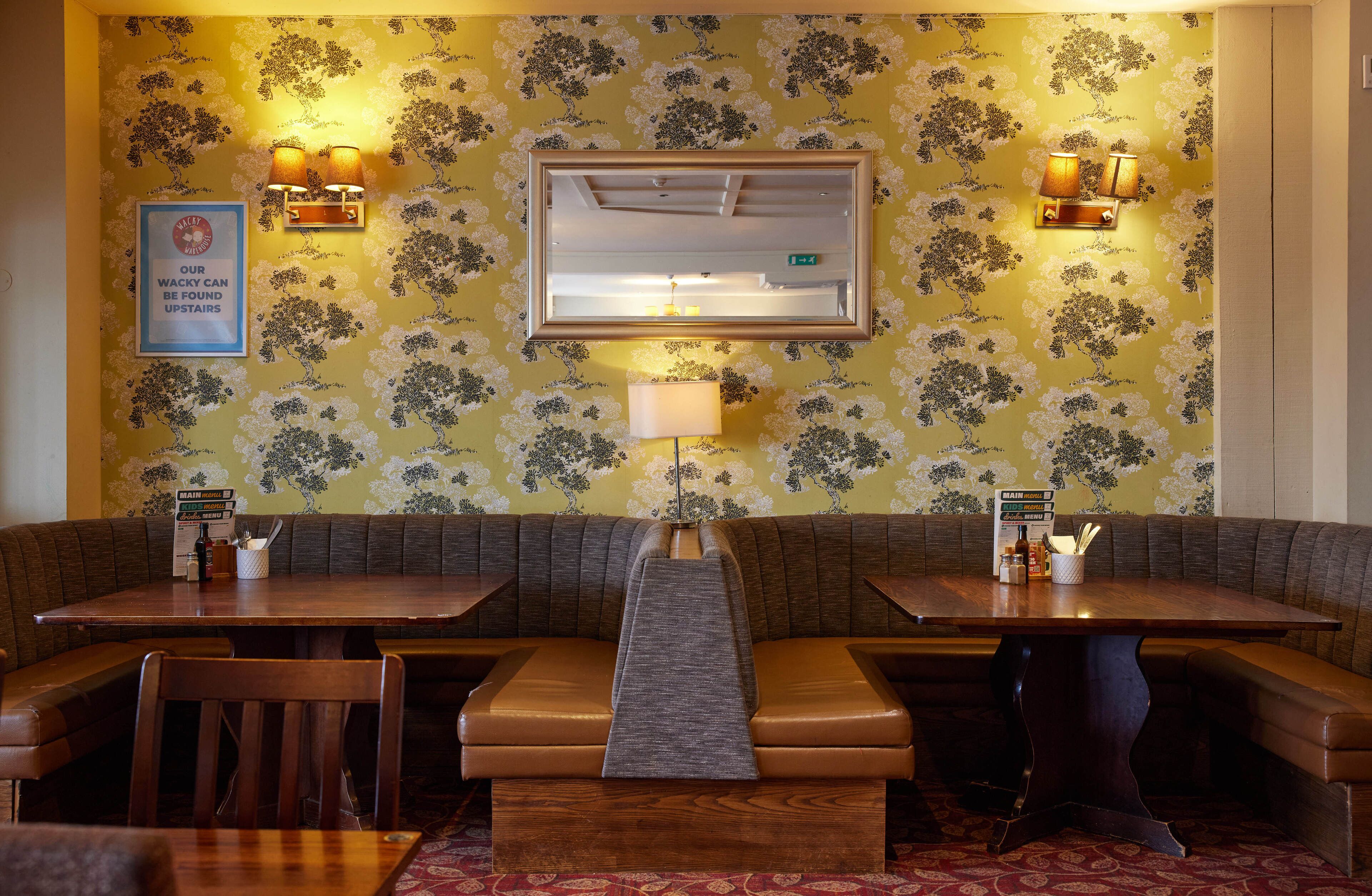 Un restaurante con asientos tipo cabina, una mesa de madera y un papel tapiz estampado.