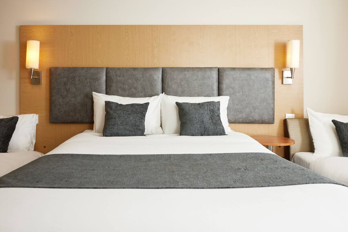 A hotel room with a large bed, two bedside tables, and a wooden headboard.