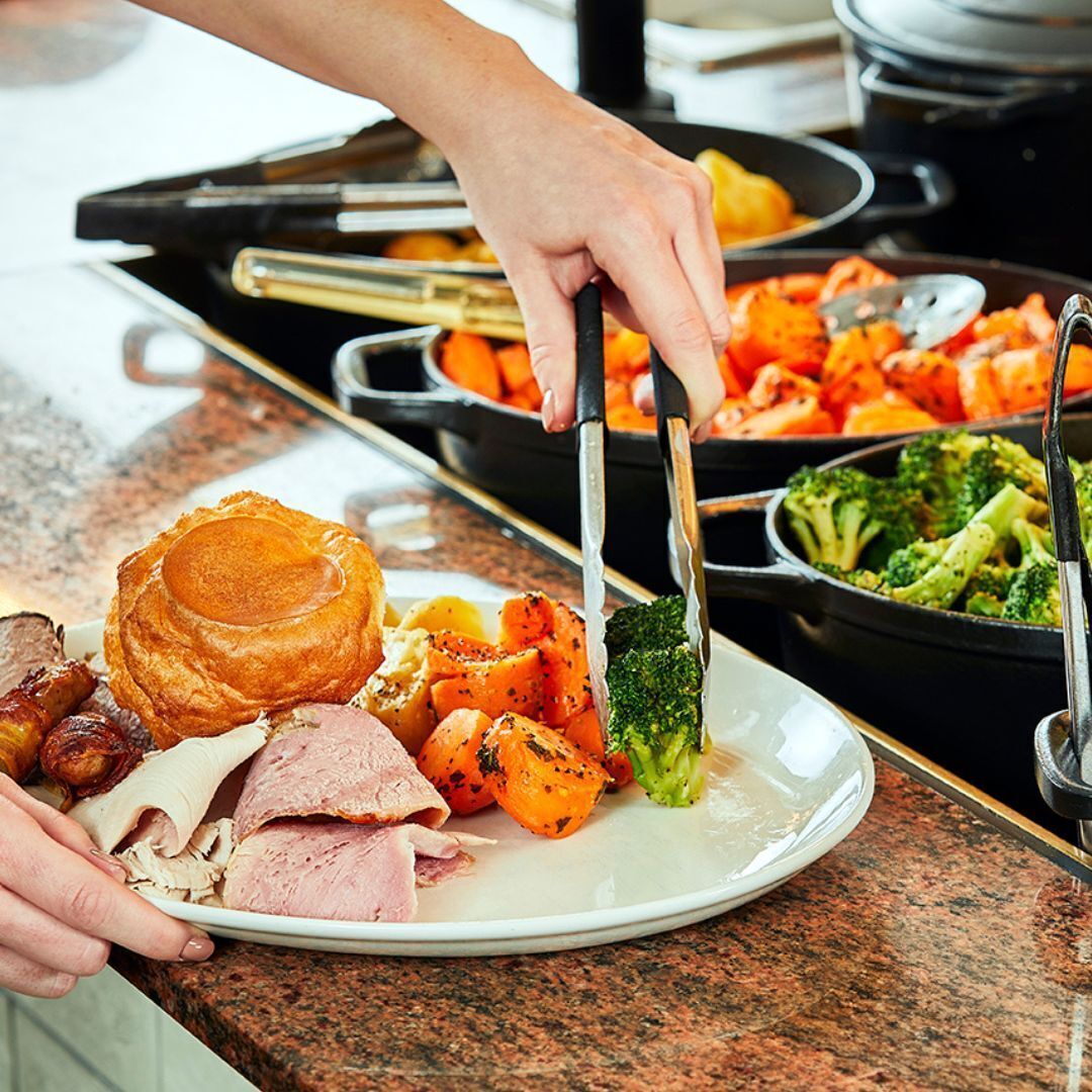 A buffet with various dishes including roasted meats, vegetables, and a large piece of bread.