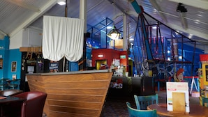 A restaurant with a high ceiling, wooden counter, and blue chairs. - The Quays By Greene King Inns (Northampton)