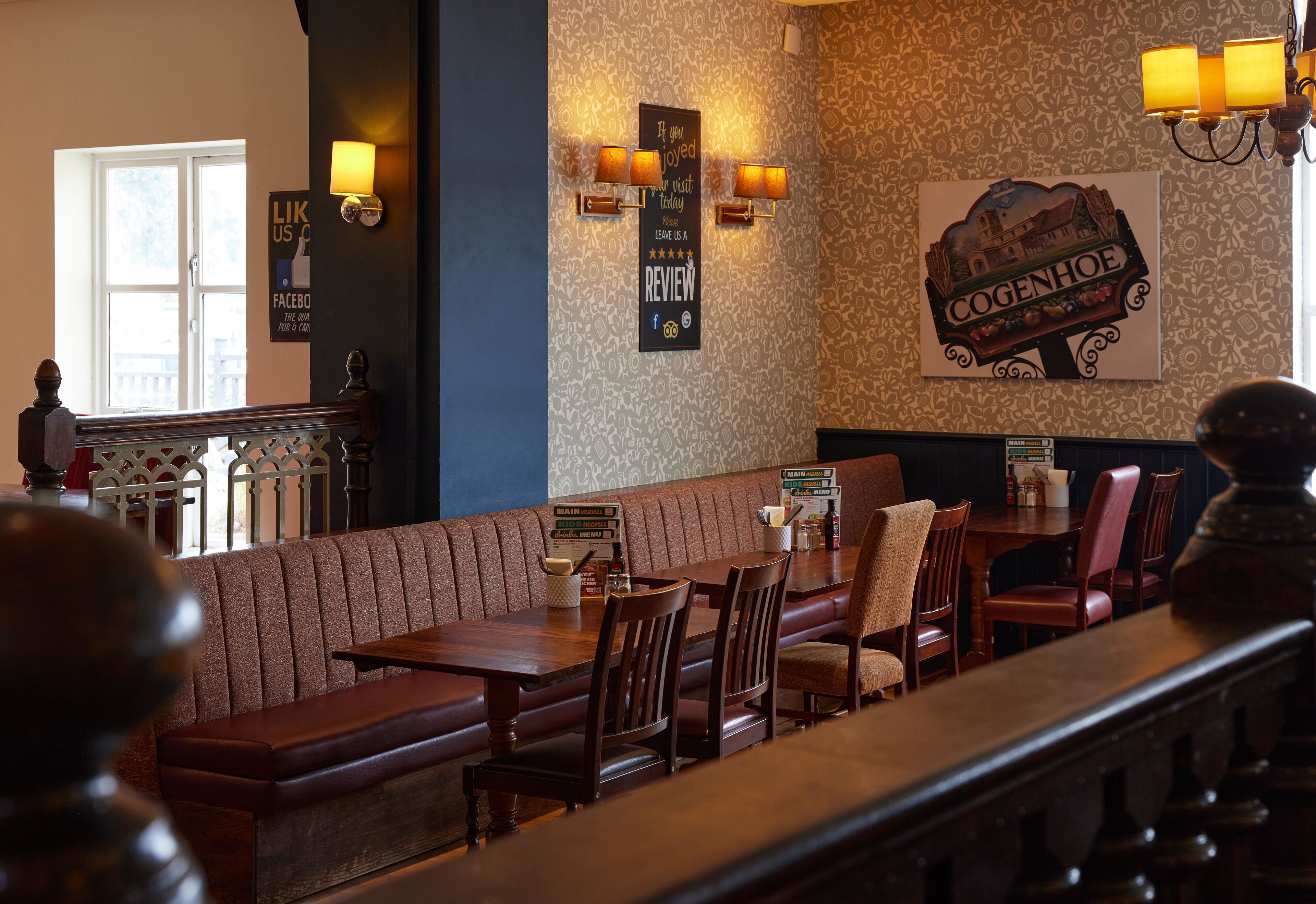 A restaurant with wooden booths, a high ceiling, and a patterned wall.