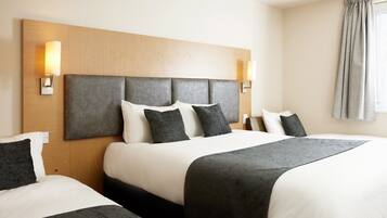 A hotel room with two beds, a wooden headboard, and two wall-mounted lamps.