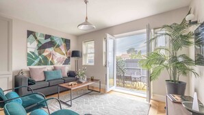 A modern living room with a sofa, chairs, a coffee table, a painting, and a potted plant. - Modern 2 Bed Oasis -Parking & Garden - By Tempstay (Berkshire)