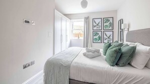 A bedroom with a bed, a window, and wall-mounted artwork. - Modern 2 Bed Oasis -Parking & Garden - By Tempstay (Berkshire)