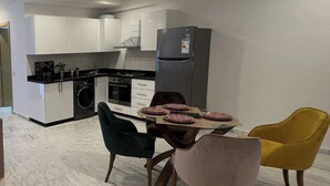 A modern kitchen with white cabinets, a grey refrigerator, and a dining table with pink plates. - 1bed Apartment - Sleeps 4 - Balcony, Wifi, Parking (Marrakech)