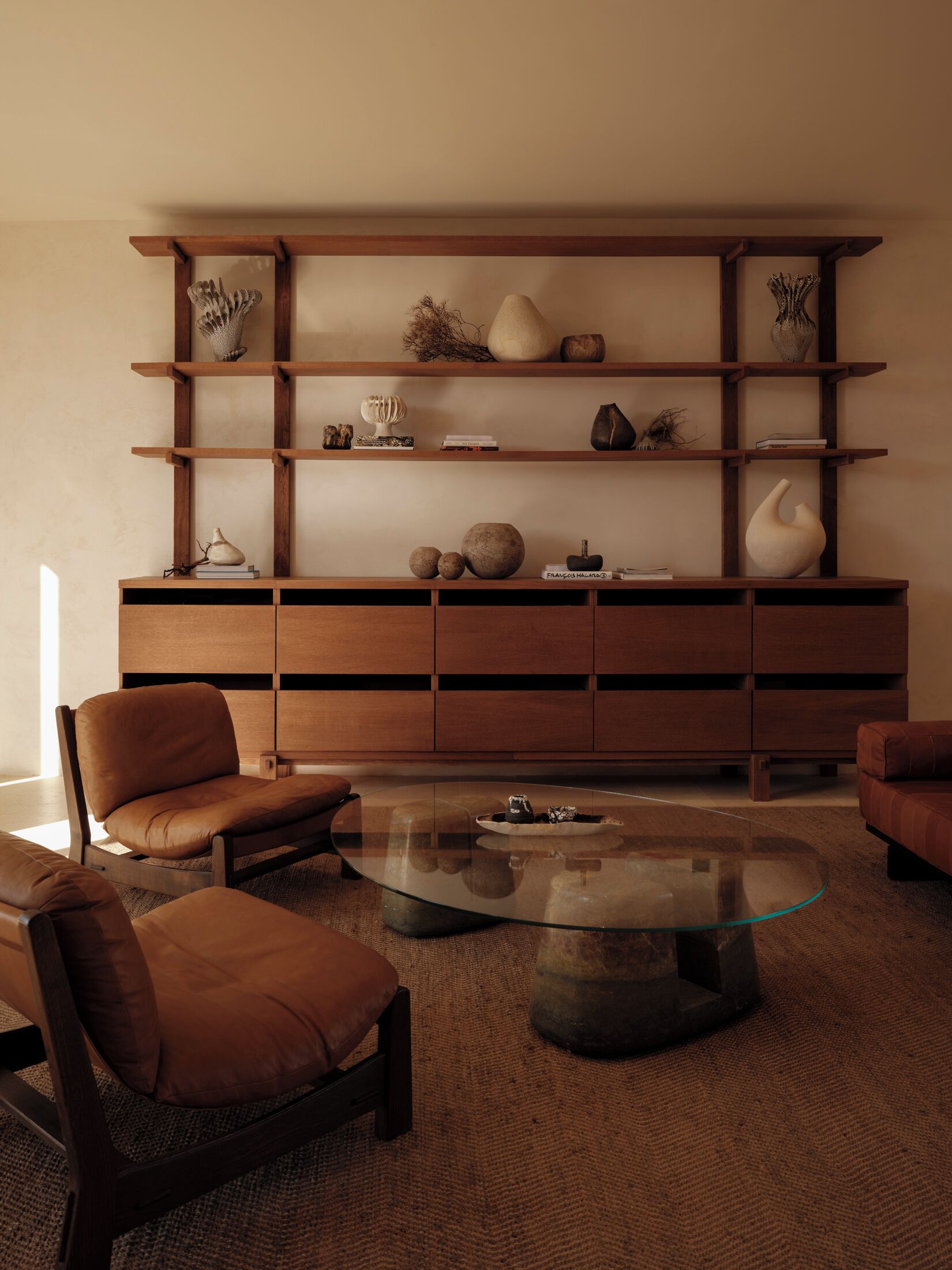 Una sala moderna con una consola de madera, sillones de cuero y una mesa de centro de vidrio.
