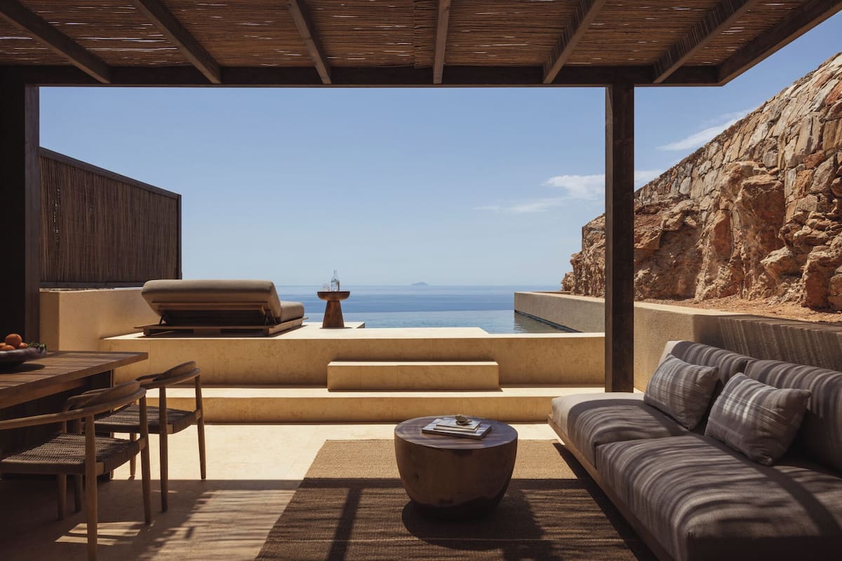 A modern outdoor living area with a stone wall, a wooden table, and a sofa.