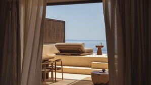 A balcony with a sofa, chairs, and a table, overlooking a body of water. - Gundari (Folegandros)