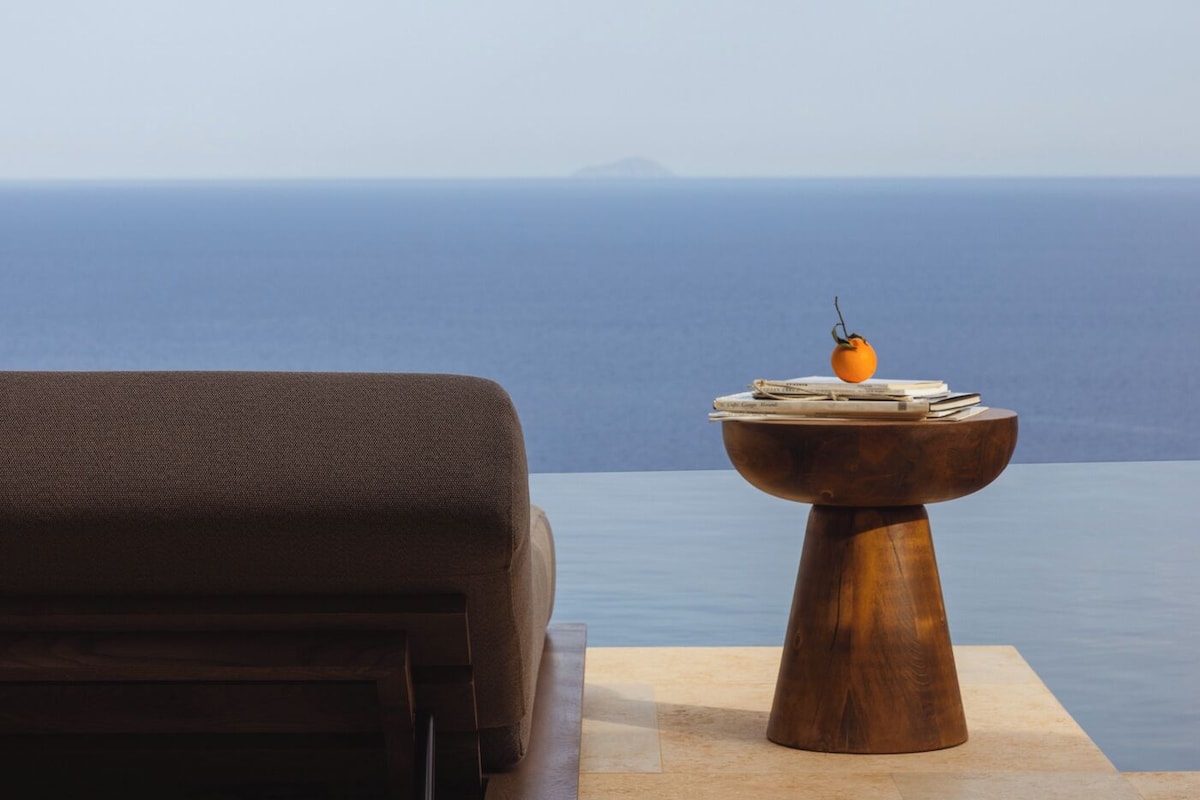 A lounge area with a sofa and a wooden table with books and a fruit.