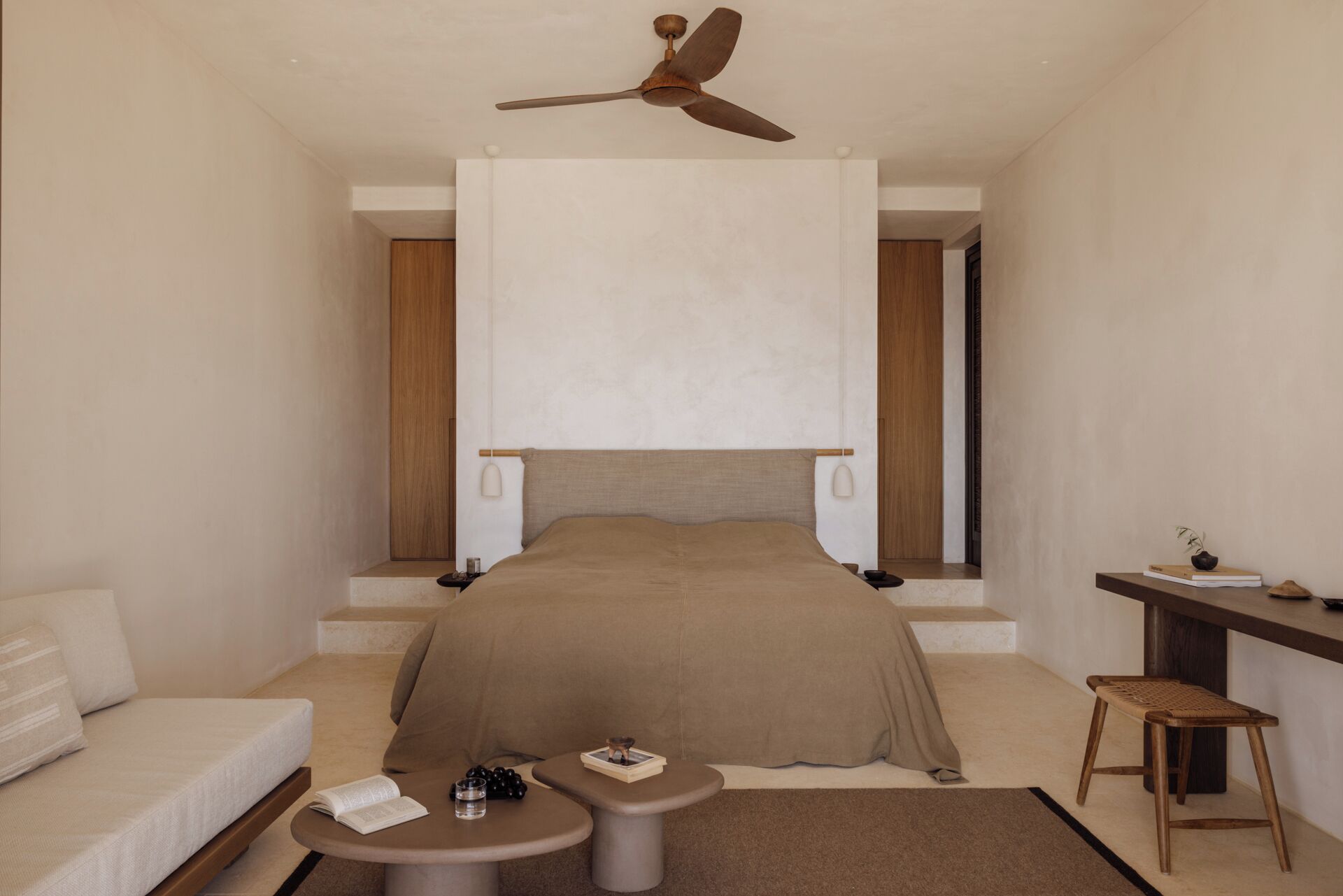 A modern hotel room with a bed, bedside tables, a desk, and a ceiling fan.