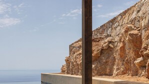 A modern outdoor seating area with a stone wall, a pool, and a clear view of the sea. - Gundari (Folegandros)