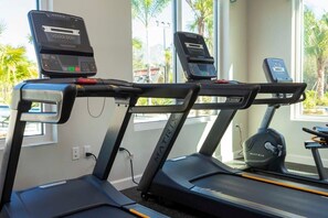 Three Matrix treadmills in a gym with large windows and a view of palm trees.