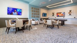 A conference room with a large screen, multiple tables, and chairs.