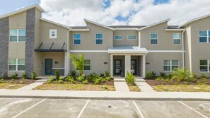 A multi-story building with a flat roof, a central entrance, and a parking lot in front. - Magnificient 4Bd w/ Pool @ Storey Lake Resort 2648 (Kissimmee)