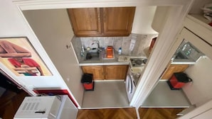 Une cuisine compacte avec des meubles de rangement en bois, un évier, un lave-linge et un petit plan de travail.