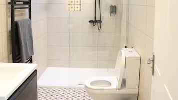 Un baño moderno con ducha, inodoro y lavamanos.