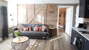 A modern living room with a sofa, coffee table, and a brick wall. - Cathedral Superior Apartment (Worcester)