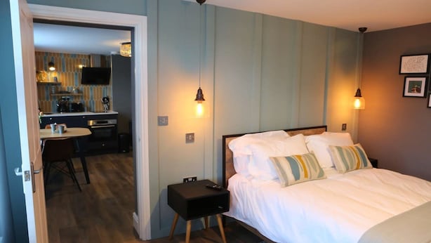 Une chambre à coucher comprenant un lit, des tables de chevet et un coin bureau avec une chaise.