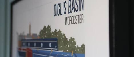 A framed picture of a river scene with boats and trees, labeled "DIGLIS BASIN WORCESTER".