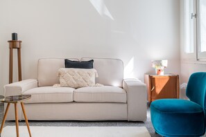 A living room with a sofa, a side table, a floor lamp, and a chair.