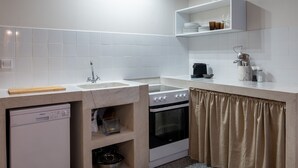 Une cuisine compacte équipée d’un lave-vaisselle, d’une cuisinière et d’un four, d’un évier et d’une étagère pour ranger les ustensiles de cuisine.