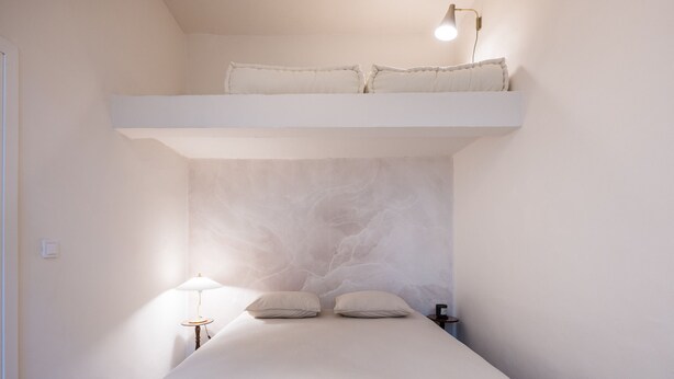 Une chambre avec un lit superposé, une table de chevet avec une lampe et un luminaire fixé au mur.