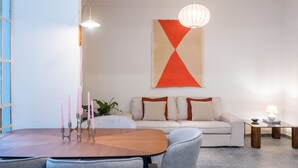 Un salon moderne avec un canapé, une table à manger et un luminaire suspendu.
