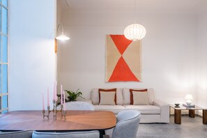Un salon moderne avec un canapé, une table à manger et un luminaire suspendu.