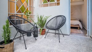 Un petit espace extérieur aménagé avec deux chaises et une plante en pot.