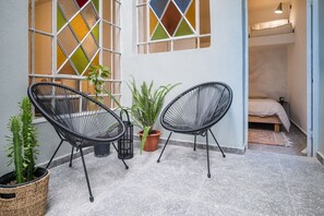 Un petit espace extérieur aménagé avec deux chaises et une plante en pot.