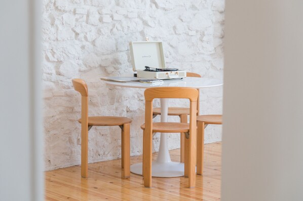 A room with a white table, two wooden chairs, and a white wall with a textured pattern.