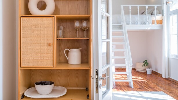 Una habitación con un armario de madera que contiene un cuenco, vasos y una jarrón.