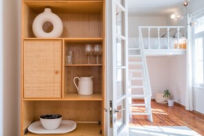 A room with a wooden cabinet containing a bowl, glasses, and a pitcher.