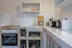 A modern kitchen with a built-in oven, a coffee maker, and a knife block. - Charlie – Timeless Charm & Modern Comfort (Athens)