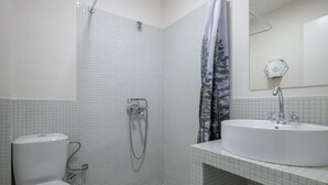 A bathroom with a toilet, shower, and sink. - Charlie – Timeless Charm & Modern Comfort (Athens)