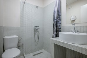A bathroom with a toilet, shower, and sink. - Charlie – Timeless Charm & Modern Comfort (Athens)