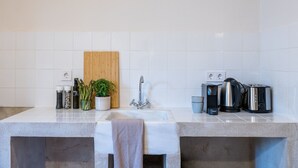 Une cuisine moderne dotée d’un plan de travail en granit, d’une planche à découper en bois, d’un évier en acier inoxydable et d’une bouilloire.