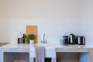 Une cuisine moderne dotée d’un plan de travail en granit, d’une planche à découper en bois, d’un évier en acier inoxydable et d’une bouilloire.