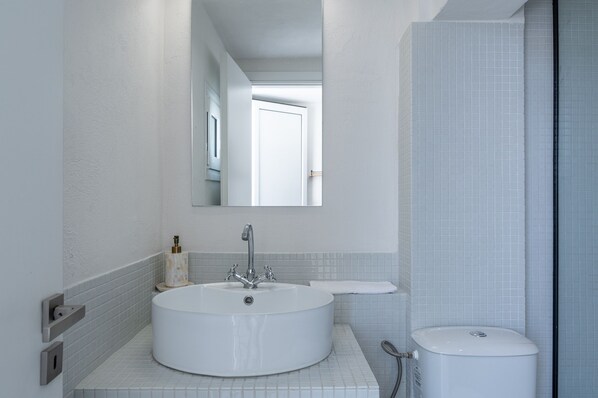 A modern bathroom with a round sink, a mirror, and a toilet.